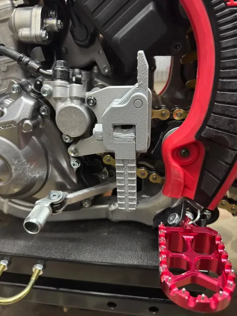 3D-printed footpeg and bracket prototype mounted on the motorcycle